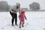 Jenna Axsel plays with Onalenna Monama as they come out to see the snow, 10 July 2023, at Jackson Dam in Alberton, South of Johannesburg.   