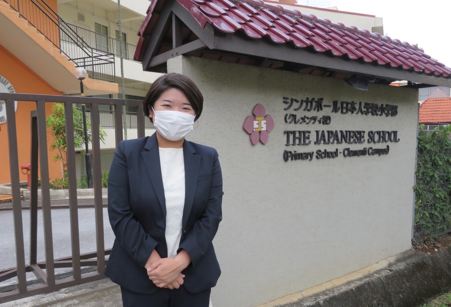 小学校の前に立つ女性