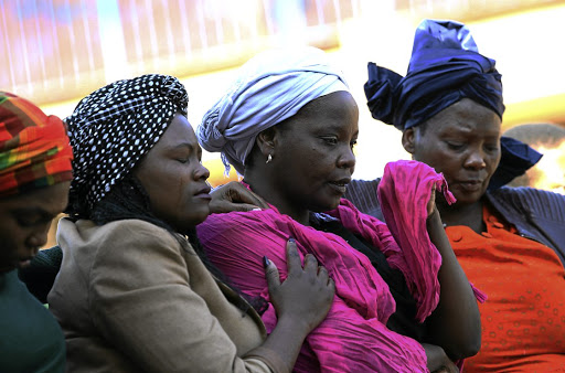 Siphiwe Khalishwa gets ready to wipe her tears as she is comforted by family members during a memorial service of her son, Luyanda Tshabalala, who was shot and killed by his father at his school Fred Norman Secondary School in Ennerdale.