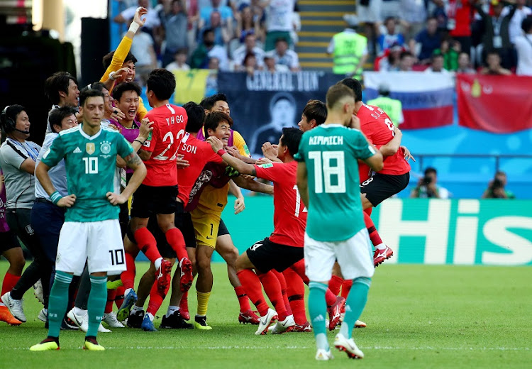 South Korea's Kim Young-gwon celebrates scoring their first goal with teammates as Germany's Mesut Ozil looks dejected.