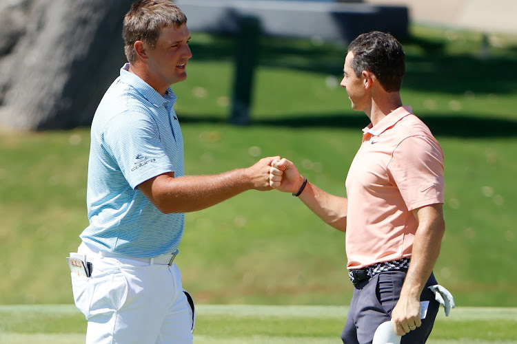 Bryson DeChambeau of the United States and Rory McIlroy of Northern Ireland bump fists