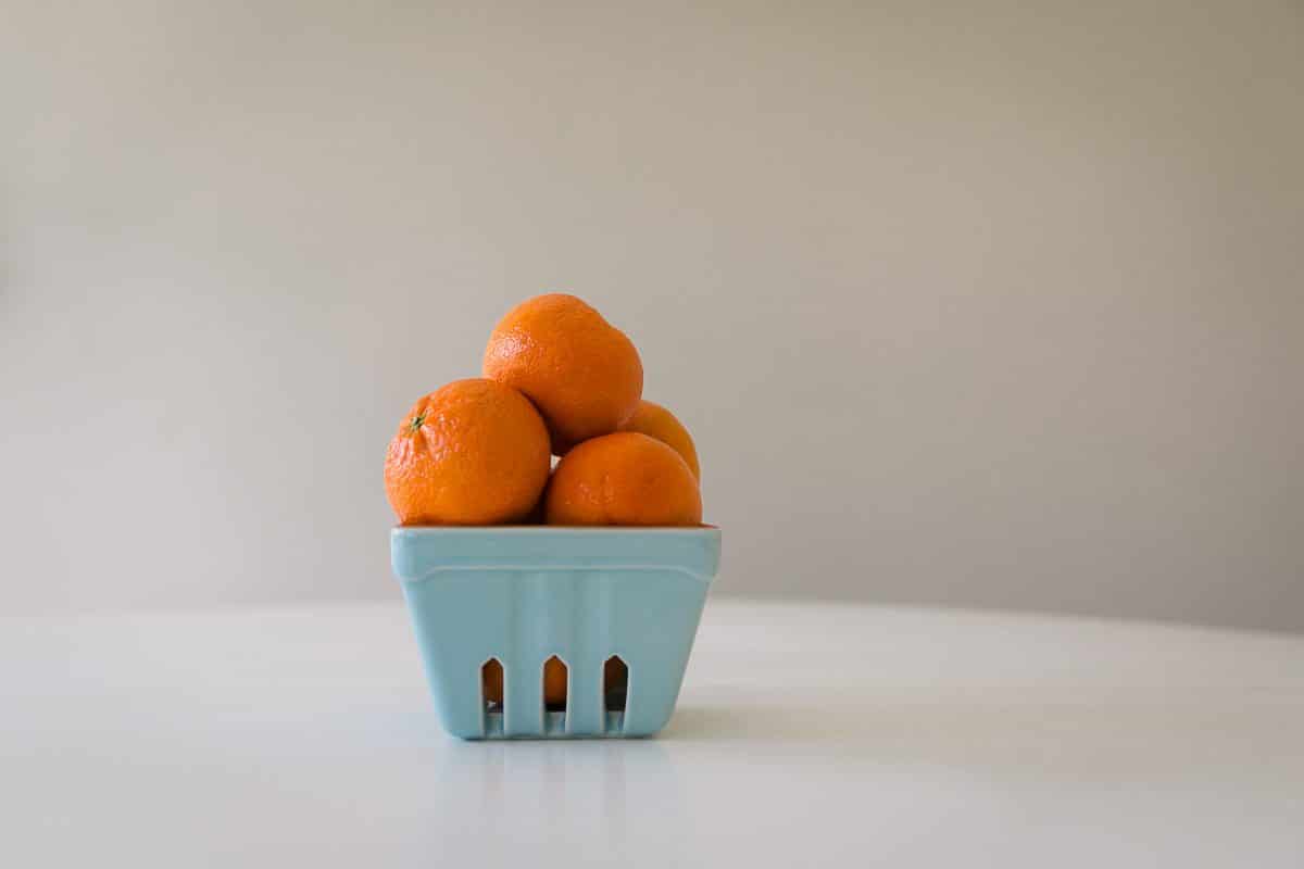 Oranges stacked in a blue container on a white table 