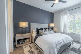 Model bedroom with furniture, large window, and wood finish flooring