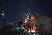 Search and recue teams use heavy machinery to get through tons of rubble from a site in Adıyaman where a building collapsed following two earthquakes that rattled the city on February 6, 2023