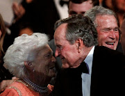 Former US President George. H.W. Bush (C) smiles at his wife Barbara (L), as their son former President George W. Bush (R) laughs, during the 