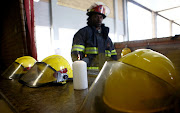 Central fire station commander, Chico Nyathi looks at a candle that is placed next to helmets of three firefighters who lost their lives trying to extinguish a fire at a building in Johannesburg CBD on September 6 2018


