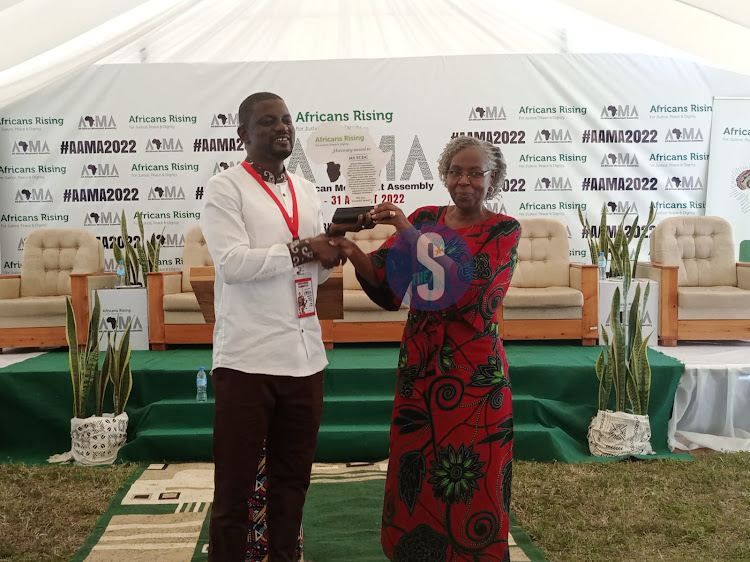 Africans Rising co-coordinator Muhammed Lamin hands MS Training Center for Development Center Executive director Makena Mwobobia a branded piece during the All African Movement Assembly in Arusha on August 31,2022