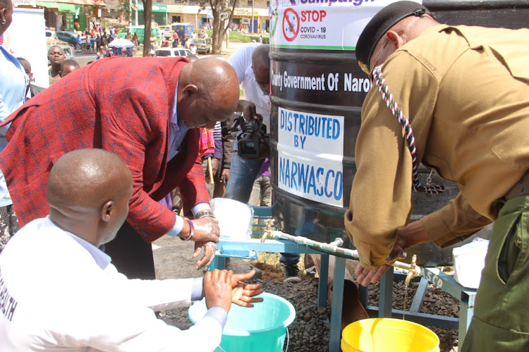 Narok Governor Samuel Tunai and Narok county commissioner Samuel Kimiti wash their hands during the launch of plastic tanks to promote handwashing on Friday.