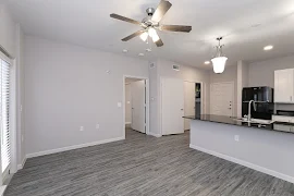 Living room with wood-inspired flooring, light walls, and ceiling fan