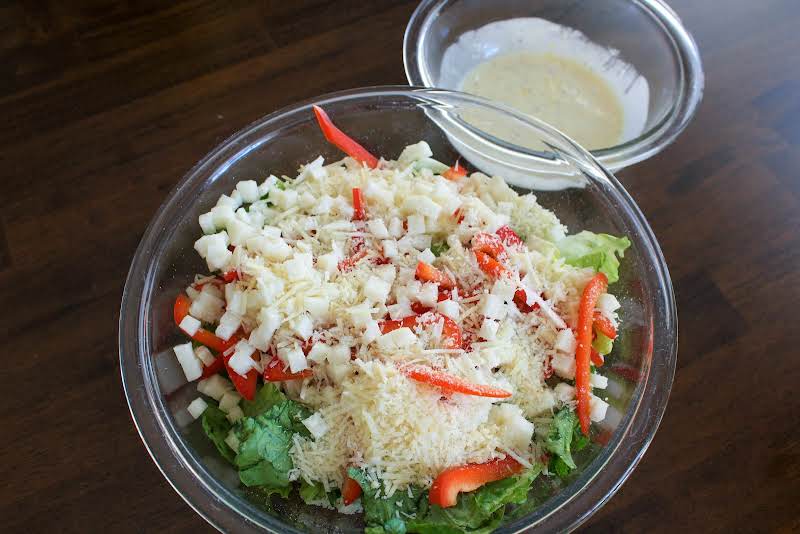 Romaine, Jicama, Bell Pepper, Tortilla Strips, Cheese, And Dressing In A Bowl.