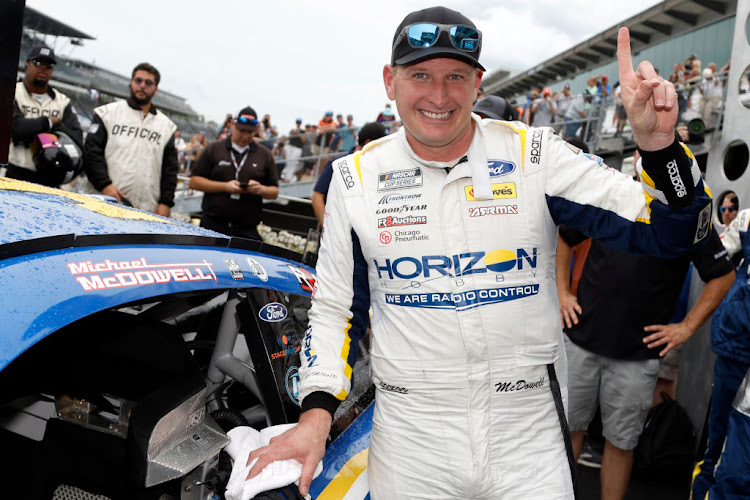 Michael McDowell poses next to his winner sticker in victory lane after winning the NASCAR Cup Series Verizon 200 at the Brickyard at Indianapolis Motor Speedway on August 13 2023 in Indiana.