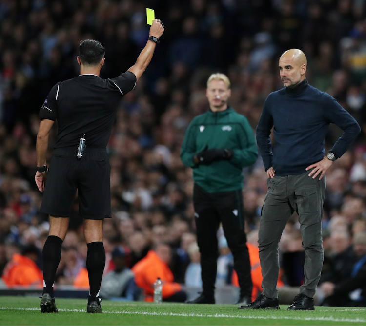 Manchester City manager Pep Guardiola is shown a yellow card by referee Serdar Gozubuyuk