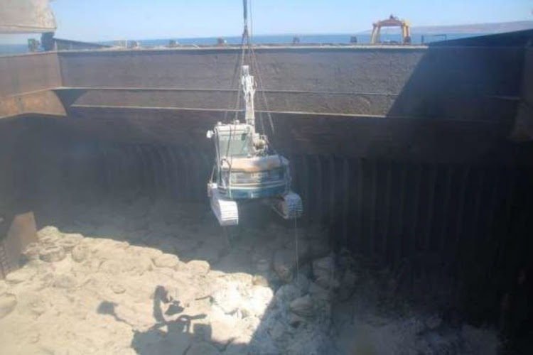 An excavator is lowered into the bulk carrier NS Qingdao to remove its chemical cargo. The remaining cargo is to be dumped 250km offshore. Picture: SA MARITIME SAFETY AUTHORITY