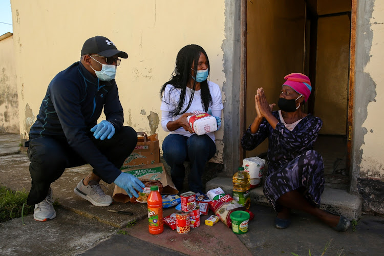 New Brighton resident Mike Bukani and the Thembi Losi Foundation's Nhonho Losi deliver a food parcel to Pumla Chithwa, right