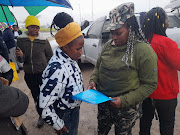 Operation Dudula secretary Daniswa Jaxa (in camouflage) promises 21-year-old job seeker Athini Thwalani a better life after delivering a memorandum to local companies demanding that they employ locals. 