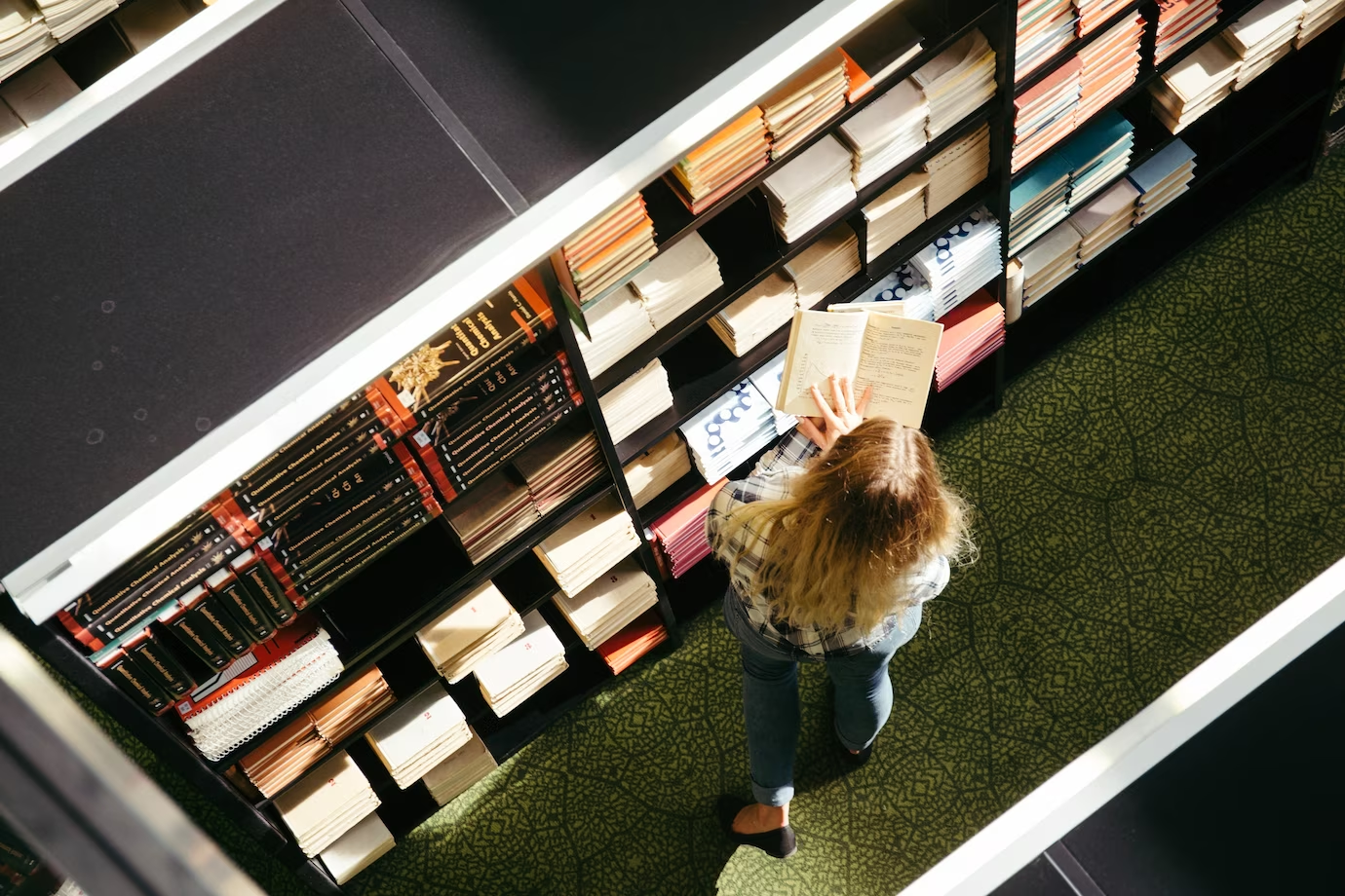 A young woman engrossed in reading a book from the top books recommended on Cambridge Reading Lists.