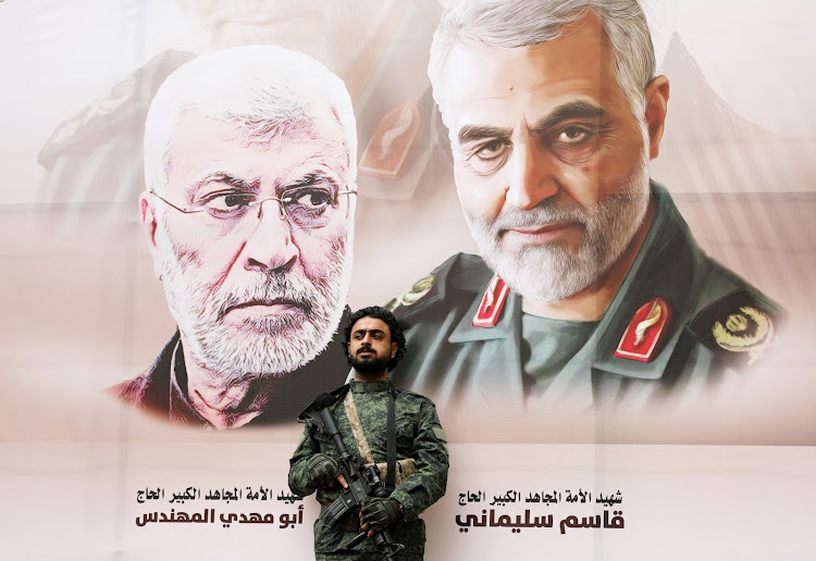 A Houthi militant stands by a billboard with posters of Iraqi militia commander Abu Mahdi al-Muhandis and Iranian military commander Qassem Soleimani during a rally by Houthi supporters to denounce the US killing of both commanders, in Sanaa, Yemen, on January 6, 2020.