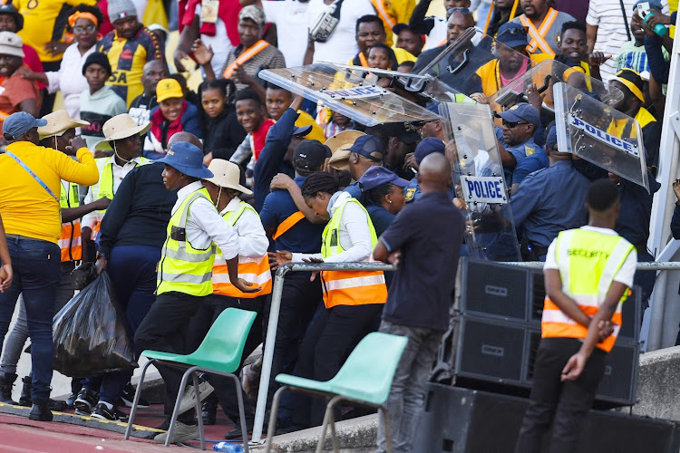 Kaizer Chiefs coach Arthur Zwane and players run for cover as their fans hurl objects at them after their 1-0 loss to SuperSport United at Royal Bafokeng Stadium.