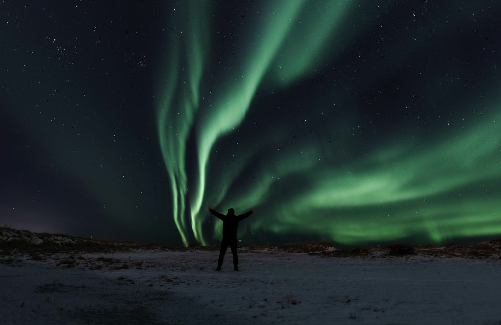 A man standing underneath to Northern Lights near Reykjavik