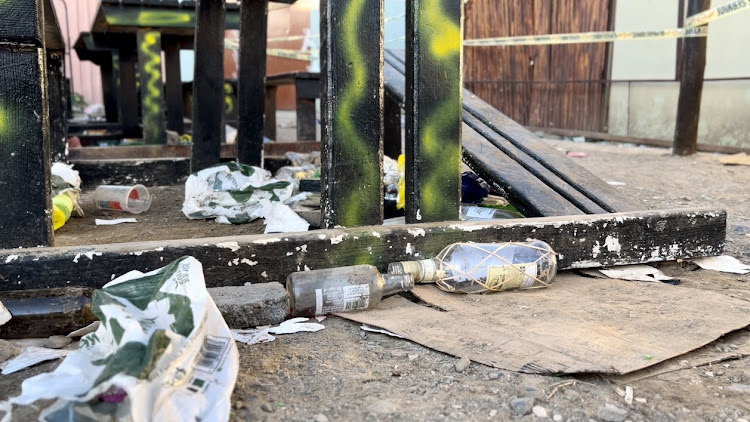 Empty alcohol bottles scattered outside the only entry and exit point at the tavern in East London after 21 teens died.