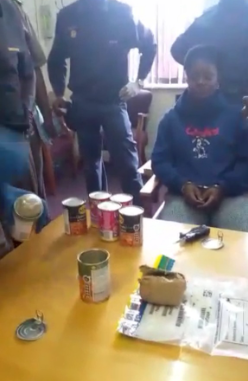 The prison warder was confronted by police at her house, where tins allegedly containing contraband were found.