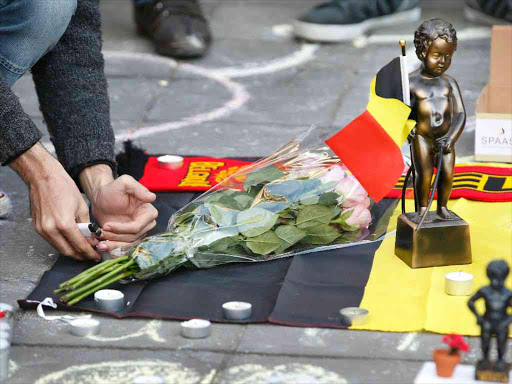 People gather around a memorial featuring a Menneken-Pis statue in Brussels following bomb attacks s in Brussels, Belgium, March 22, 2016. REUTERS/Charles Platiau