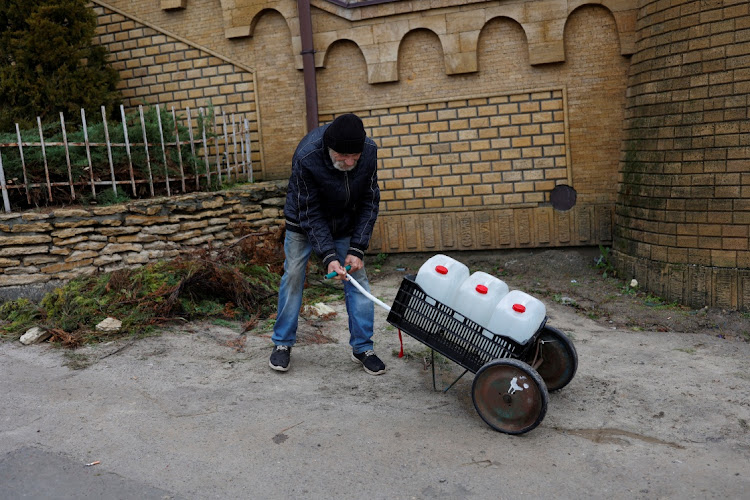 A man tries to carry water containers near Dnipro river after Russia's military retreat from Kherson, Ukraine on November 21 2022. Picture|: REUTERS/MURAD SEZER