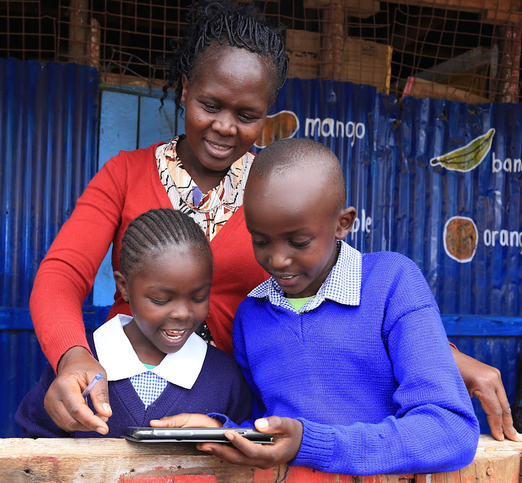 A teacher help pupils read using a tablet