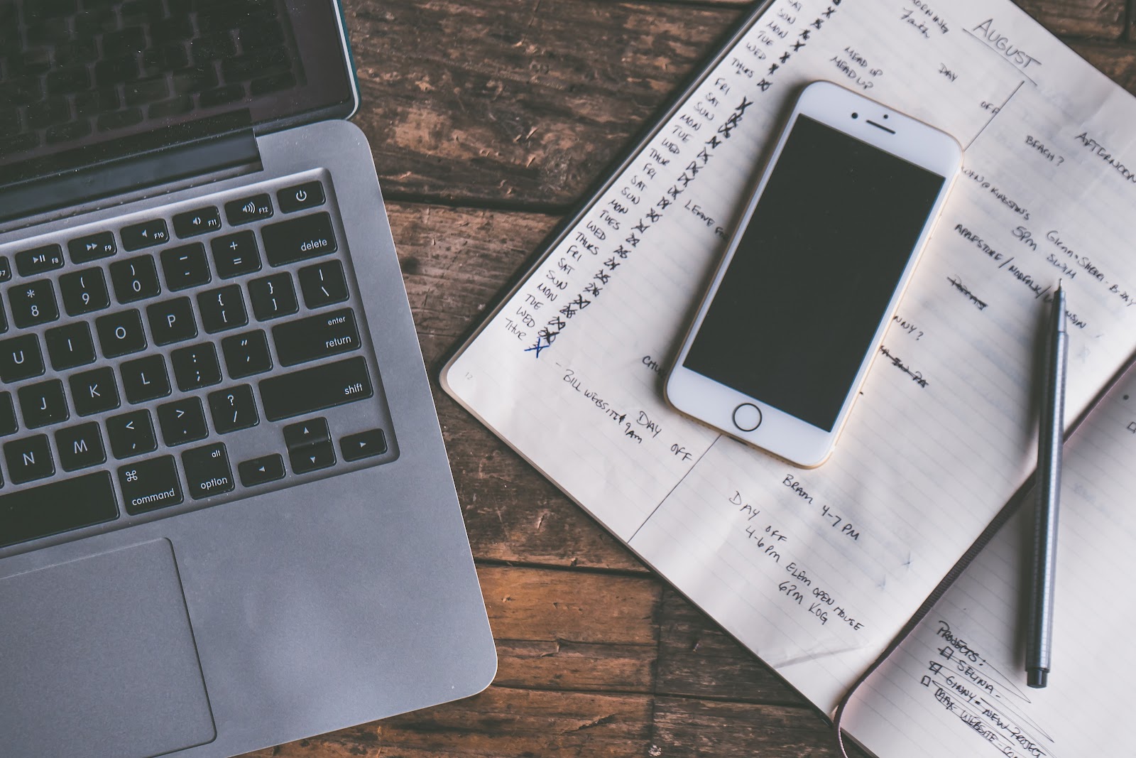 Image of Apple Mac laptop, iPhone, pen, and notebook for planning app preview.