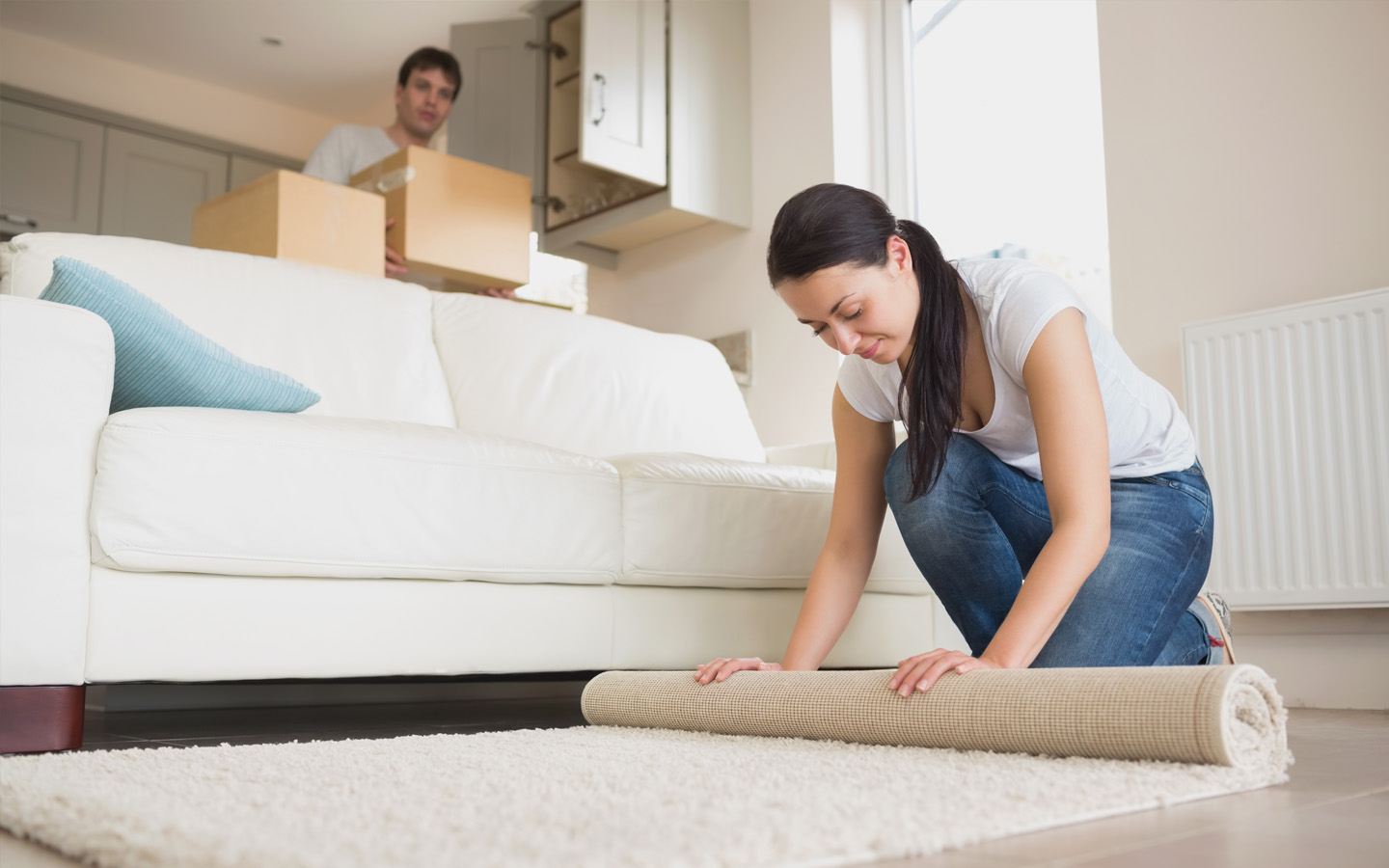 woman rolling carpet in new room