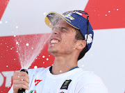 Team Suzuki Ecstar's Joan Mir celebrates with sparkling wine on the podium after winning the world championship.