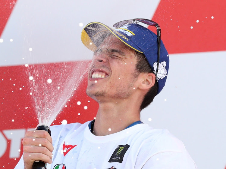 Team Suzuki Ecstar's Joan Mir celebrates with sparkling wine on the podium after winning the world championship.