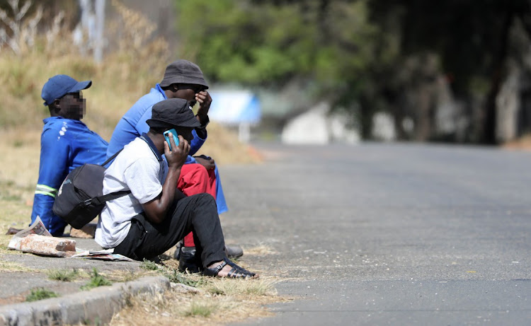 Work seekers are shown seated on a pavement in Johannesburg. File photo: ANTONIO MUCHAVE