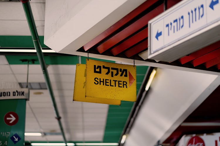 A sign in Tel Aviv's central bus station shows the way to a bomb shelter, 2021.