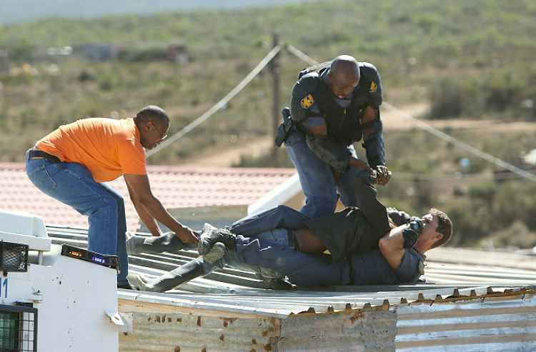 Police tackle the man who stood with a baby on the roof of his house