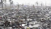 UTTER DEVASTATION: Survivors stand among the ruins of their homes yesterday after super typhoon Haiyan battered Tacloban city, in the central Philippines, on Friday. Haiyan, one of the most powerful storms on record, killed at least 10000 people in the province of Leyte. Coastal towns and the regional capital were demolished by huge waves.