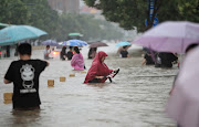 Residents wade through floodwaters on a flooded road amid heavy rainfall in Zhengzhou, Henan province, China July 20, 2021. 