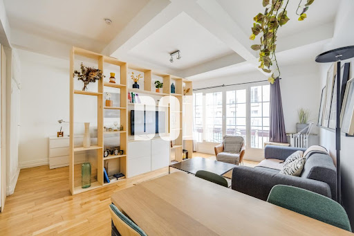 Modern living room with shelves and grey sofa in this luxury property for sale in Paris 18ème ($530,587 - 44 m²)