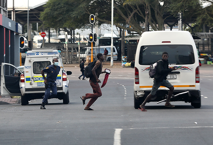 A police officer pursues two vagrants on foot in the Durban CBD on Wednesday.