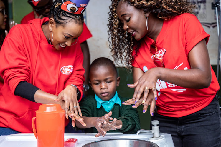 Lifebuoy soap ambassador Janet Mbugua and Heroes for Change participant Justine Nabwire teach a pupil how to was hands