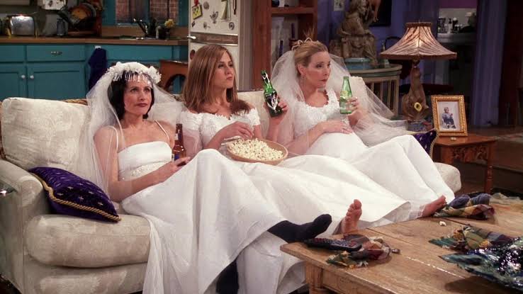 3 women wearing white gowns drinking beer
