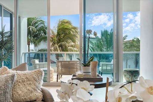 Modern living room with balcony and palm trees in this luxury property for sale in Miami Beach ($4,500,000)