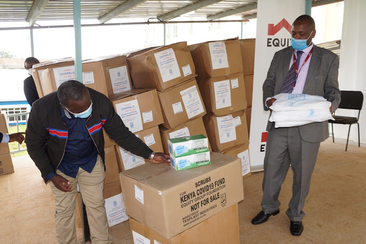 Limuru East MCA Ngigi Karuga checks on the PPE donated by Equity Foundation as Equity Bank Limuru branch Joseph Weru looks on on Monday.