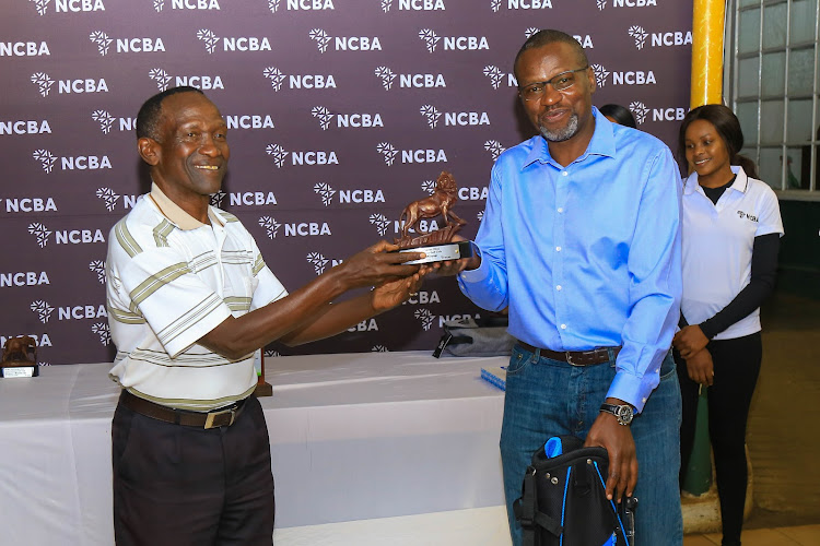 Railway Golf Club’s Samuel Mwaura (L) receives the overall winner's trophy from NCBA Group Head of Corporate Banking, Charles Omondi, during the Club's leg of the 2022 NCBA Golf Series in February.