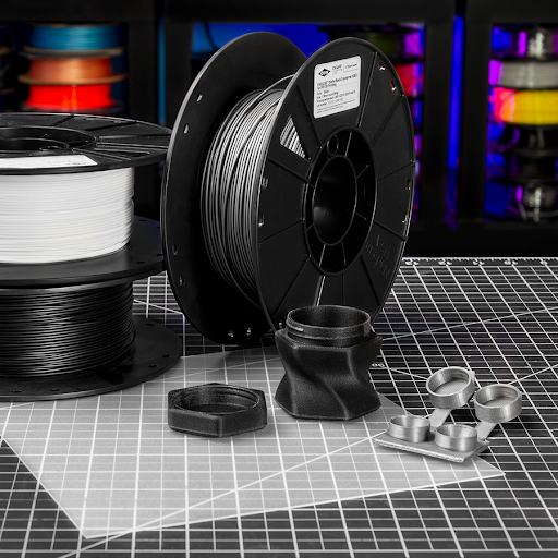 Spools of OBC filament with OBC 3D printed parts of a contact lens case and storage bottle on a LayerLock Build Surface for Polypropylene