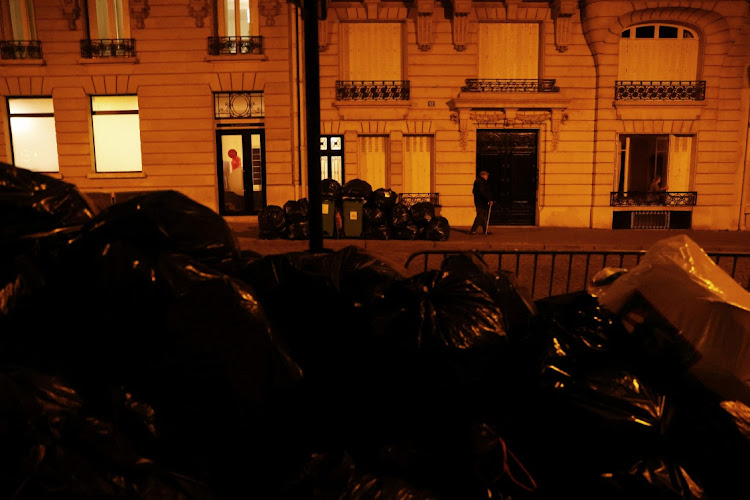 A pensioner walks past overflowing bins in a street near the Eiffel Tower as rubbish has not been collected due to a strike of rubbish collectors against the French government pension reform, in Paris, France, on March 27 2023. Picture: REUTERS/NACHO DOCE