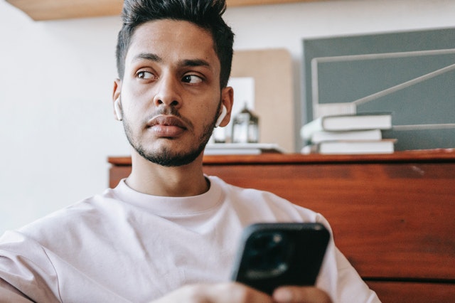 man in room looking away with phone in hand