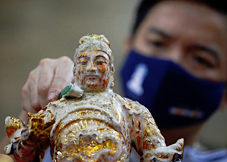 A man wearing a protective face mask washes a religious statue ahead of the Chinese Lunar New Year celebration at a temple in Jakarta, Indonesia on February 4 2021.