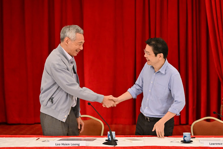 Singapore Prime Minister Lee Hsien Loong shakes hands with finance minister Lawrence Wong during a news conference at the Istana, in Singapore April 16 2022. Picture: THE STRAITS TIMES/REUTERS