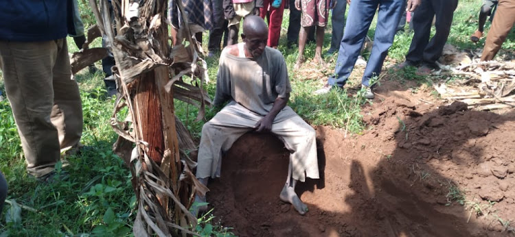 Martin Juma, 46, stares at a grave he was found digging for himself.